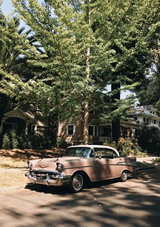 Rosa Oldtimer unter grünen Bäumen sonnige Straße Leinwandbild