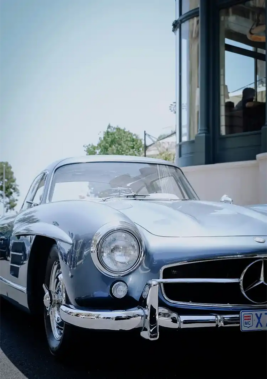 Classic silver vintage car canvas painting on a sunny street beside a modern building