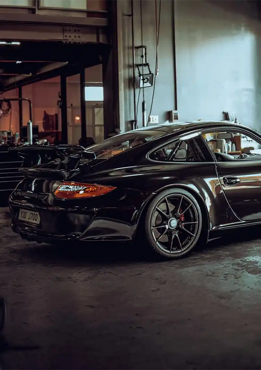 Black sports car canvas painting in an industrial garage, dark atmosphere