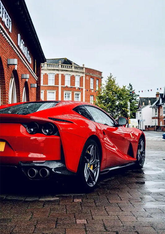 Red sports car canvas painting on a wet cobblestone street