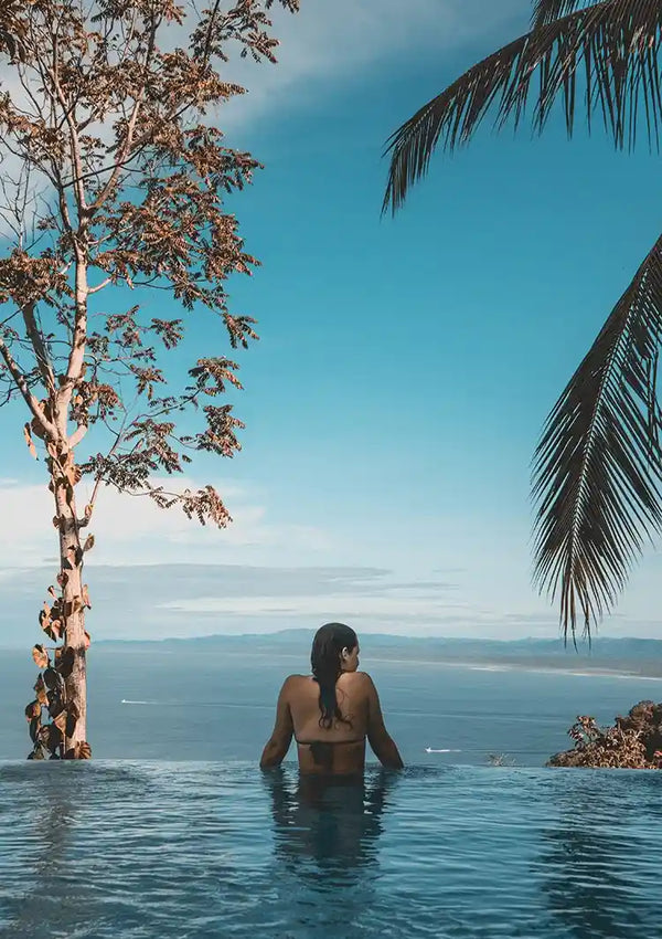 Vrouw in Overloopzwembad met Palmbomen en Tropische Zeehorizon Schilderij