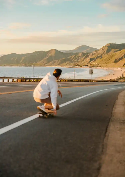 Skateboarder Op Kustweg Bij Zonsondergang Bergen Oceaan Canvas Schilderij