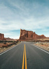 Straight Desert Road with Red Rocks and Blue Sky Canvas Print