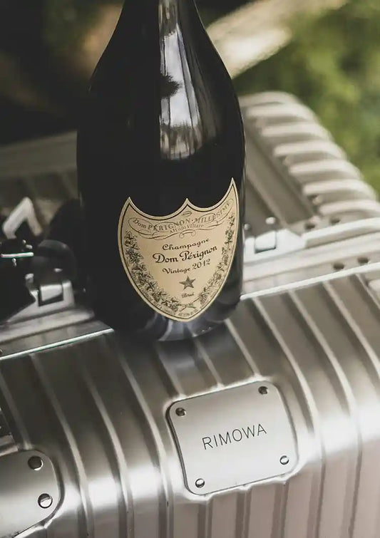 Zilveren koffer met champagnefles canvas schilderij in een sfeer van luxe reizen