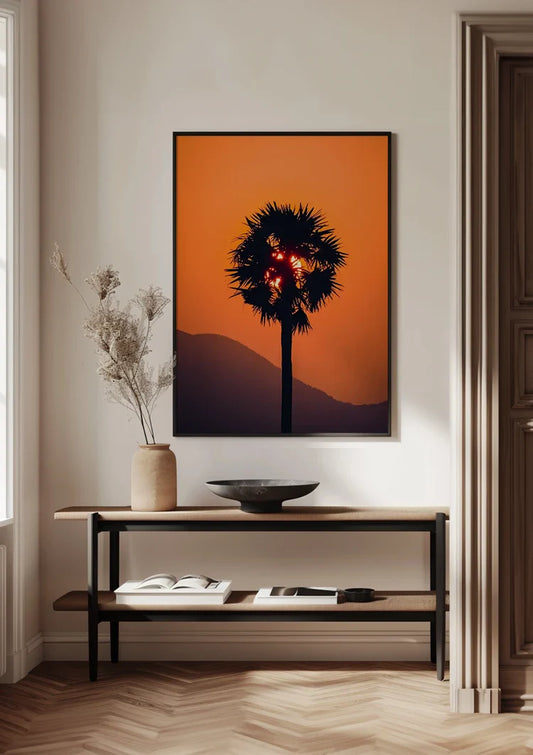 Palmboom silhouet canvas schilderij bij een oranje zonsondergang met zon door de bladeren